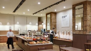 A restaurant with a buffet setup, wooden tables and chairs, and a stone accent wall. - Premier Hotel Cabin Sapporo (Sapporo)