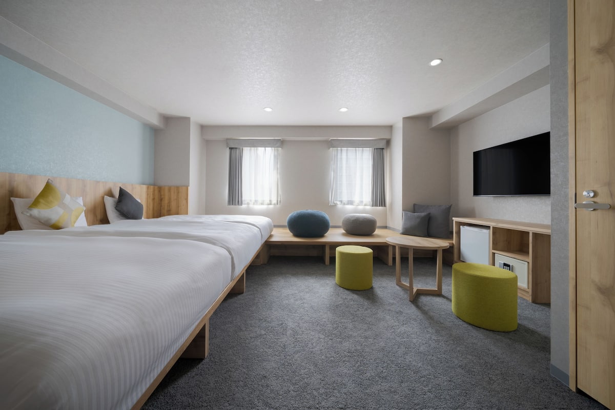 A hotel room with a large bed, a desk, a television, and a window with curtains.