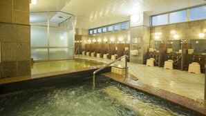 A modern indoor pool area with a central water feature, multiple changing rooms, and a glass-enclosed upper level. - Premier Hotel Cabin Sapporo (Sapporo)