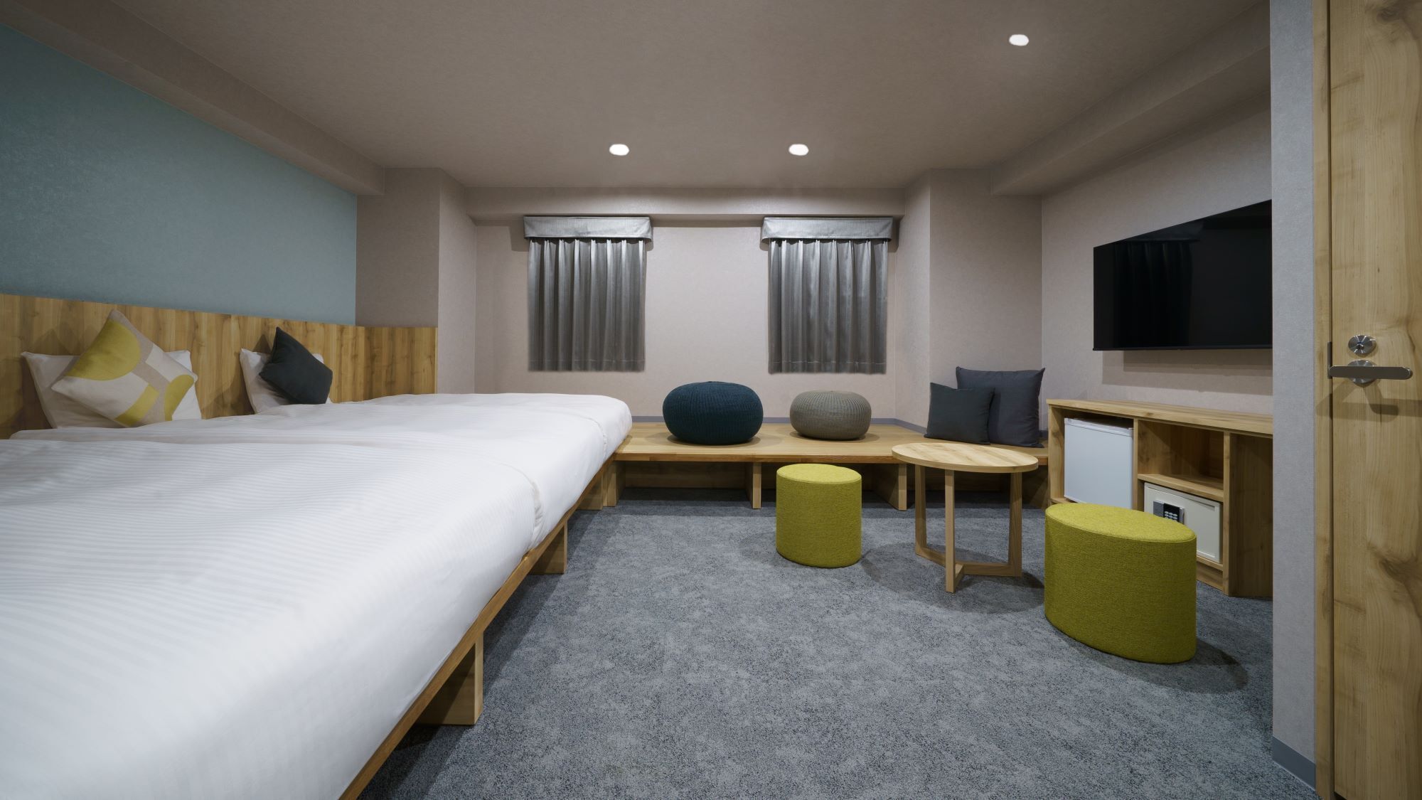 Habitación de hotel con una cama grande, un escritorio, dos sillas, televisión y un refrigerador pequeño.