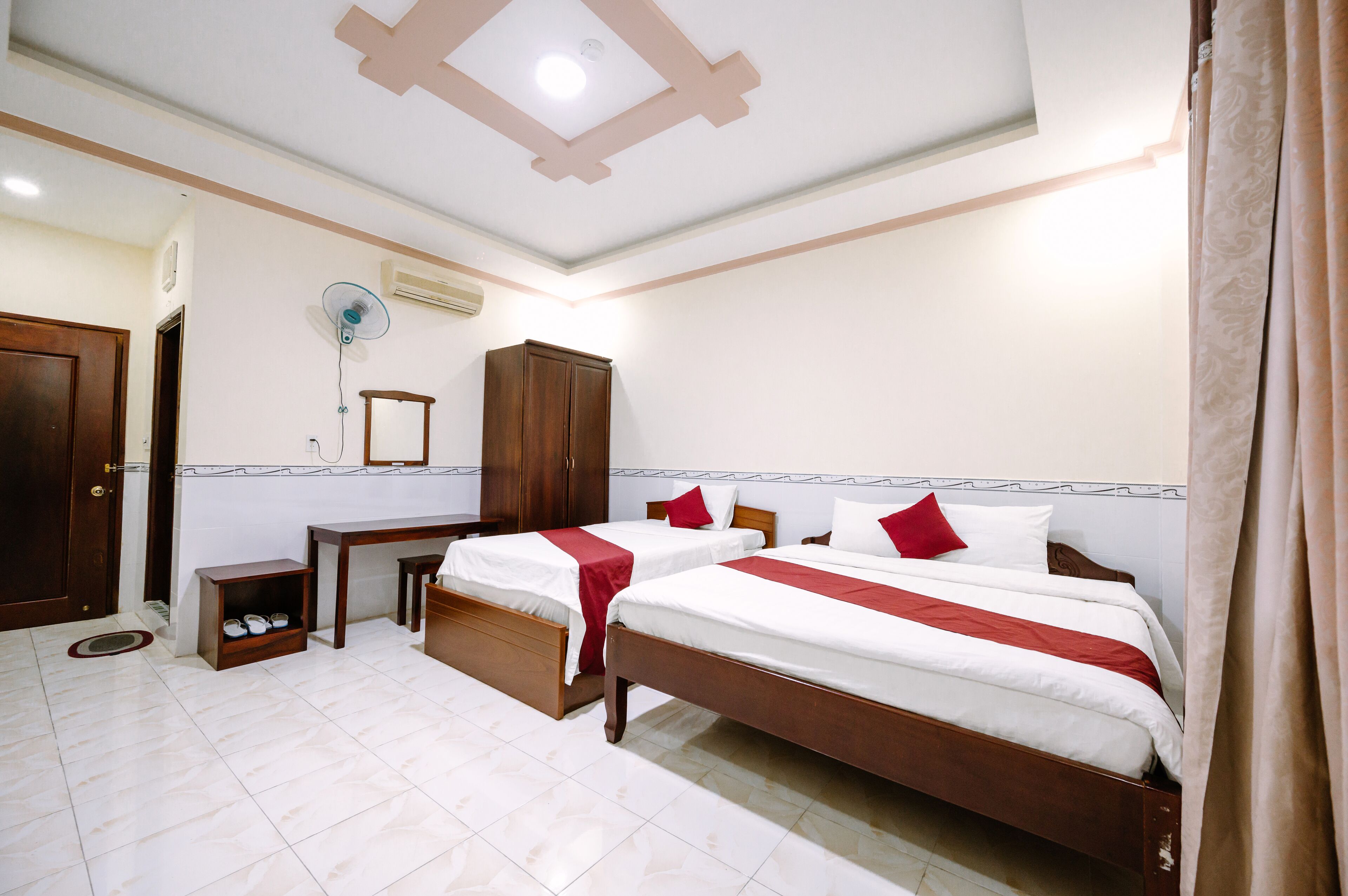 A hotel room with two beds, a wardrobe, a mirror, and a small table.
