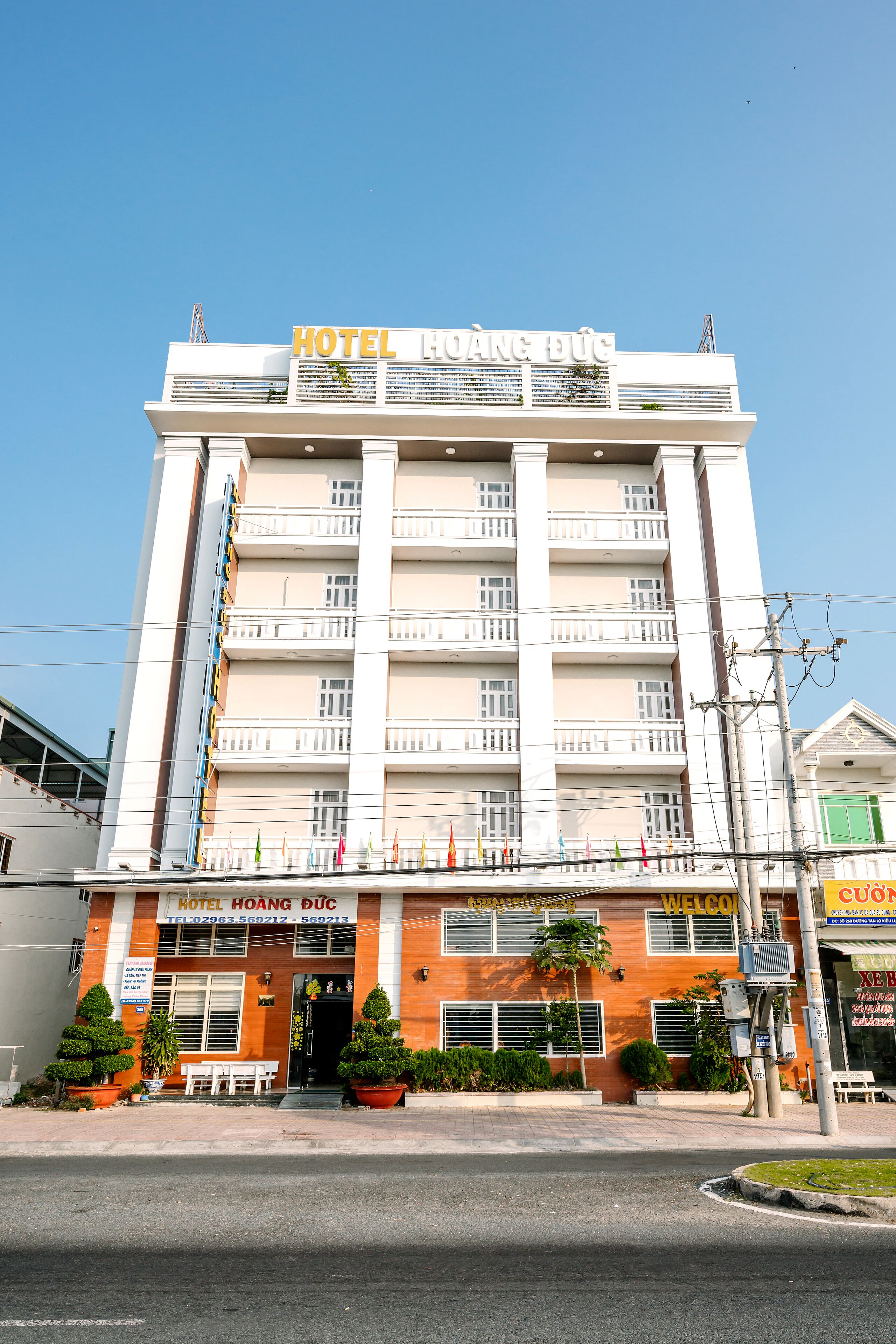 A multi-story hotel with balconies, a sign reading "HOTEL HOANG DUC," and a welcoming entrance.