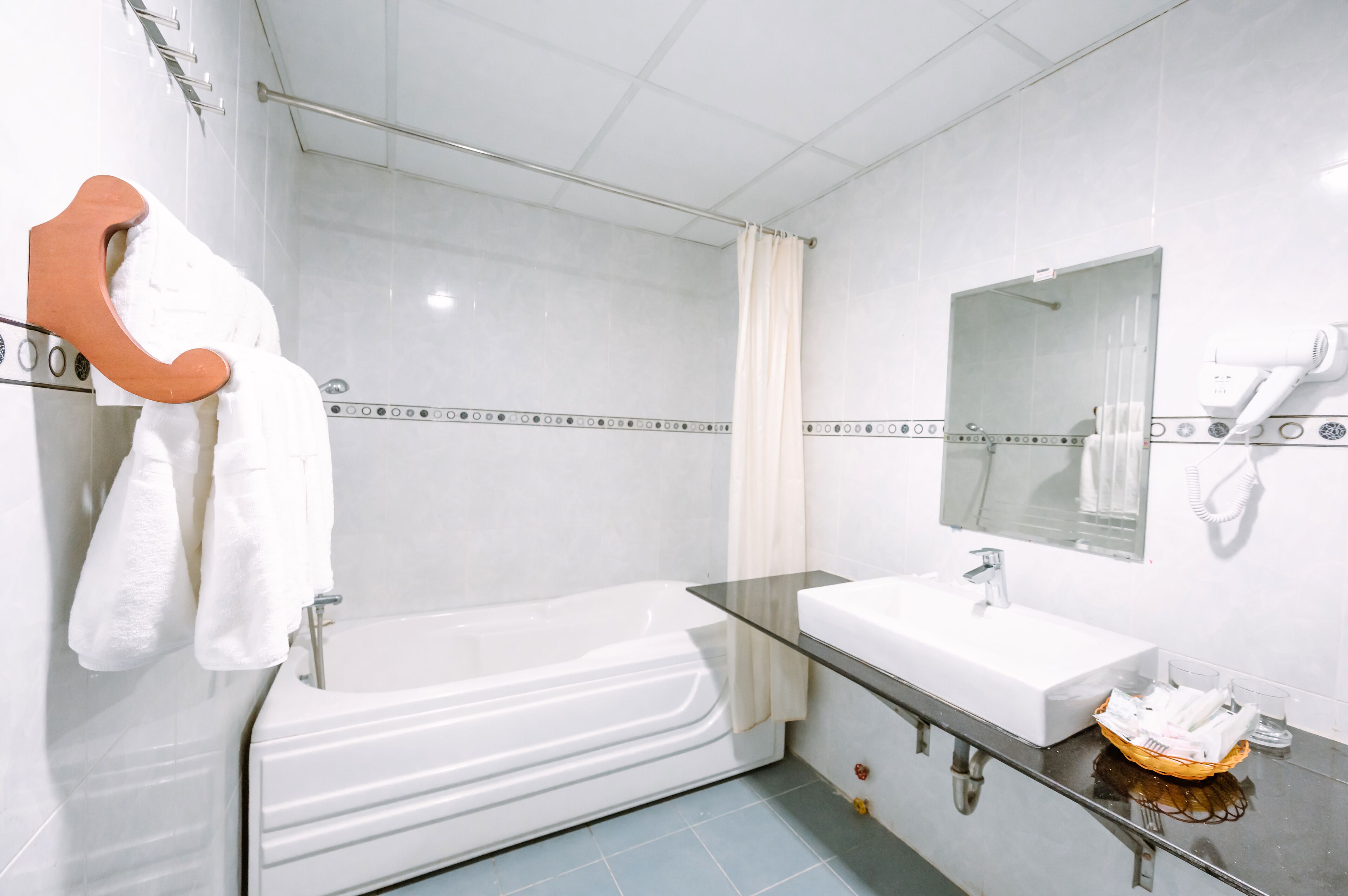 Une salle de bain moderne avec une baignoire entourée de parois en verre, un lavabo blanc et un miroir au-dessus du lavabo.