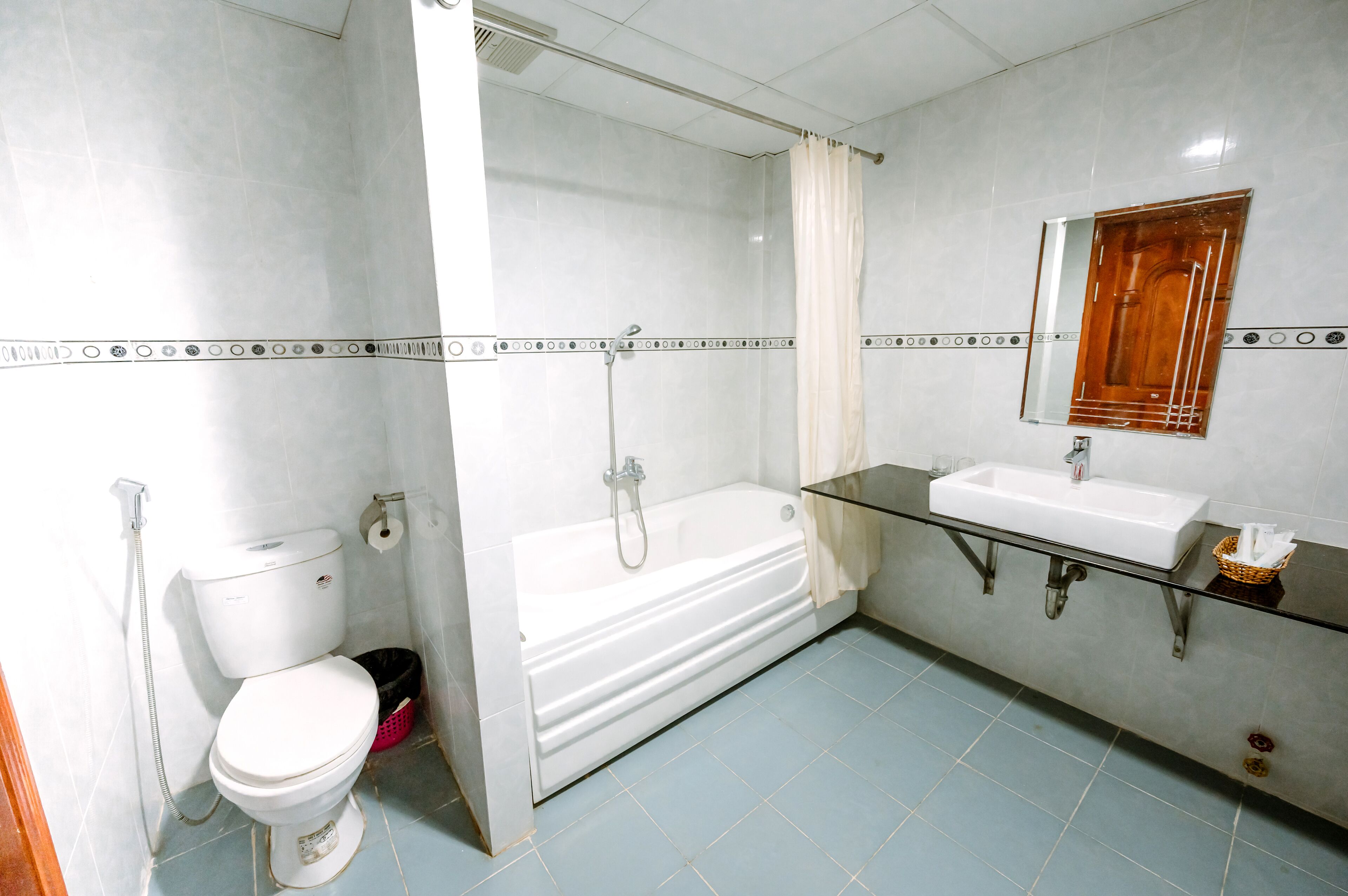 A bathroom with a toilet, a bathtub, a sink, and a mirror.