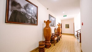 A hallway with wooden flooring, framed artwork on the walls, and a staircase at the end. - Hoang Duc Hotel (Chau Doc)