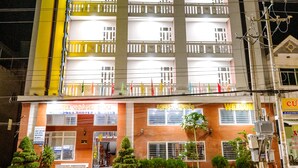 A multi-story hotel with balconies and a well-lit entrance. - Hoang Duc Hotel (Chau Doc)
