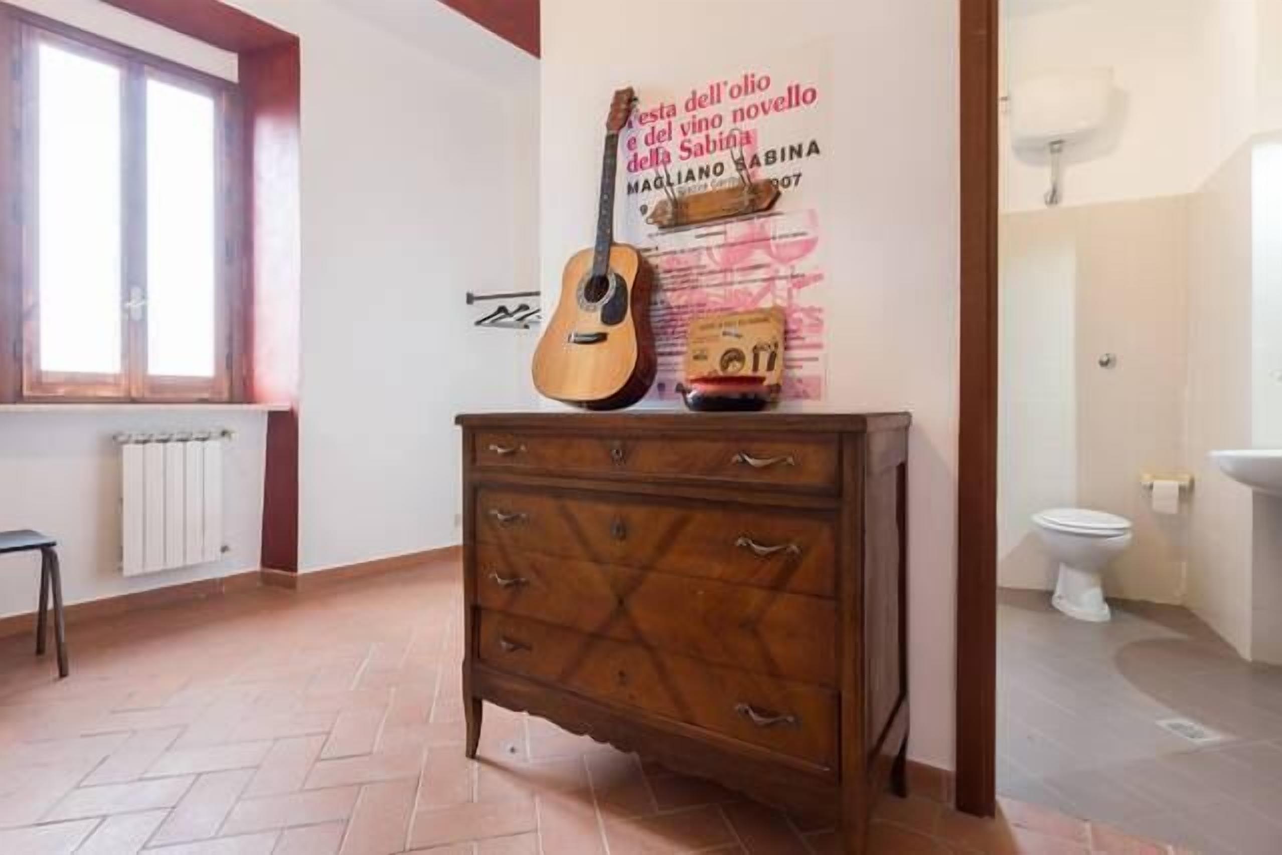 Una habitación con un aparador de madera, una guitarra y un cartel en la pared.