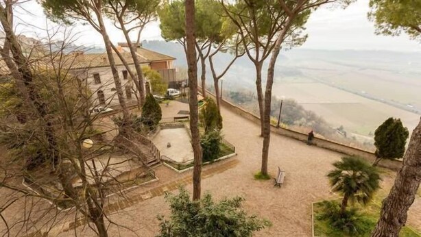 Une vue d’une propriété avec un jardin, un chemin et un bâtiment en arrière-plan.