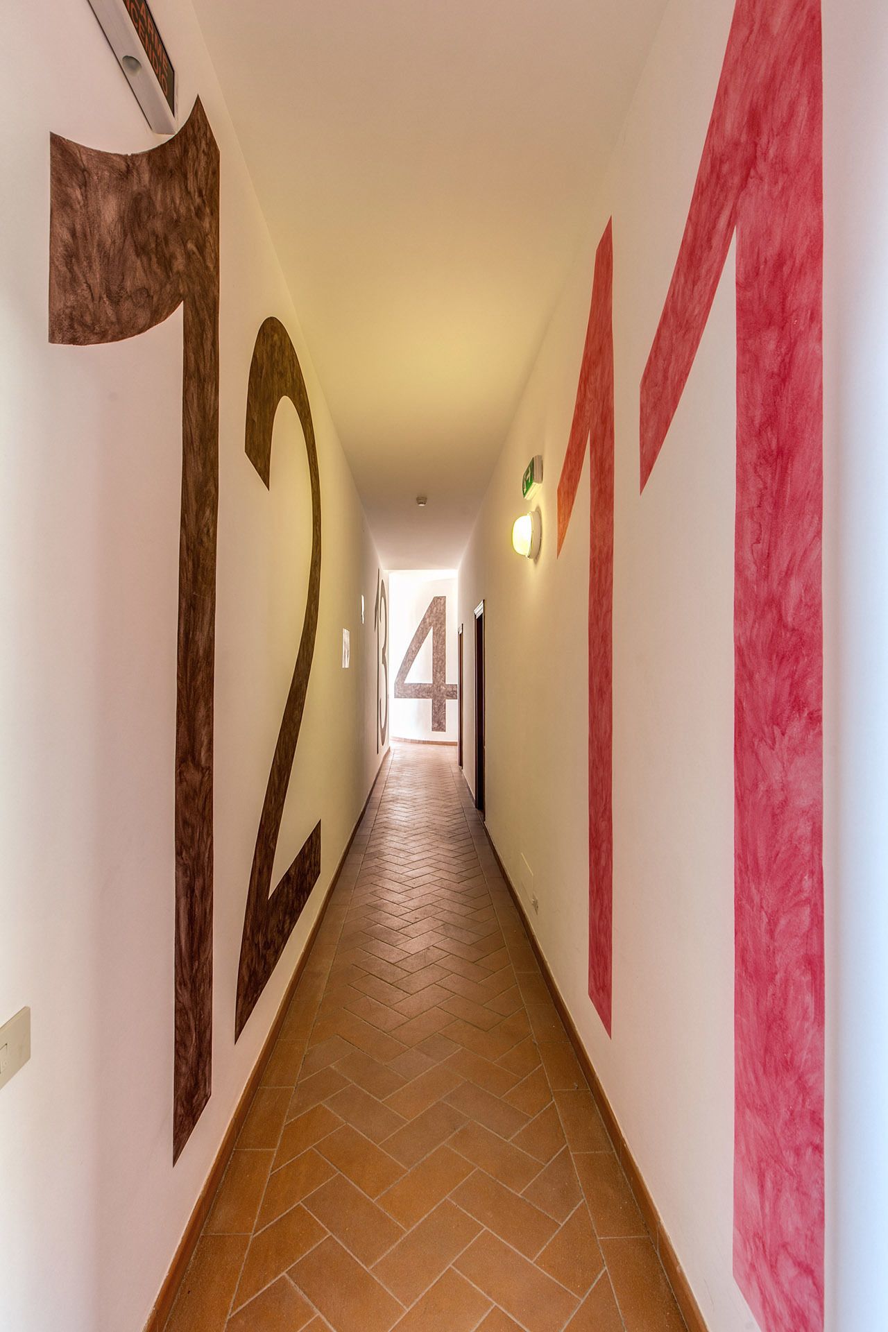 Un pasillo con números grandes en las paredes que señalan los números de habitación.
