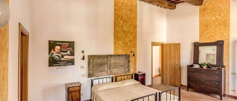 A bedroom with a bed, wooden wardrobe, and a poster on the wall.