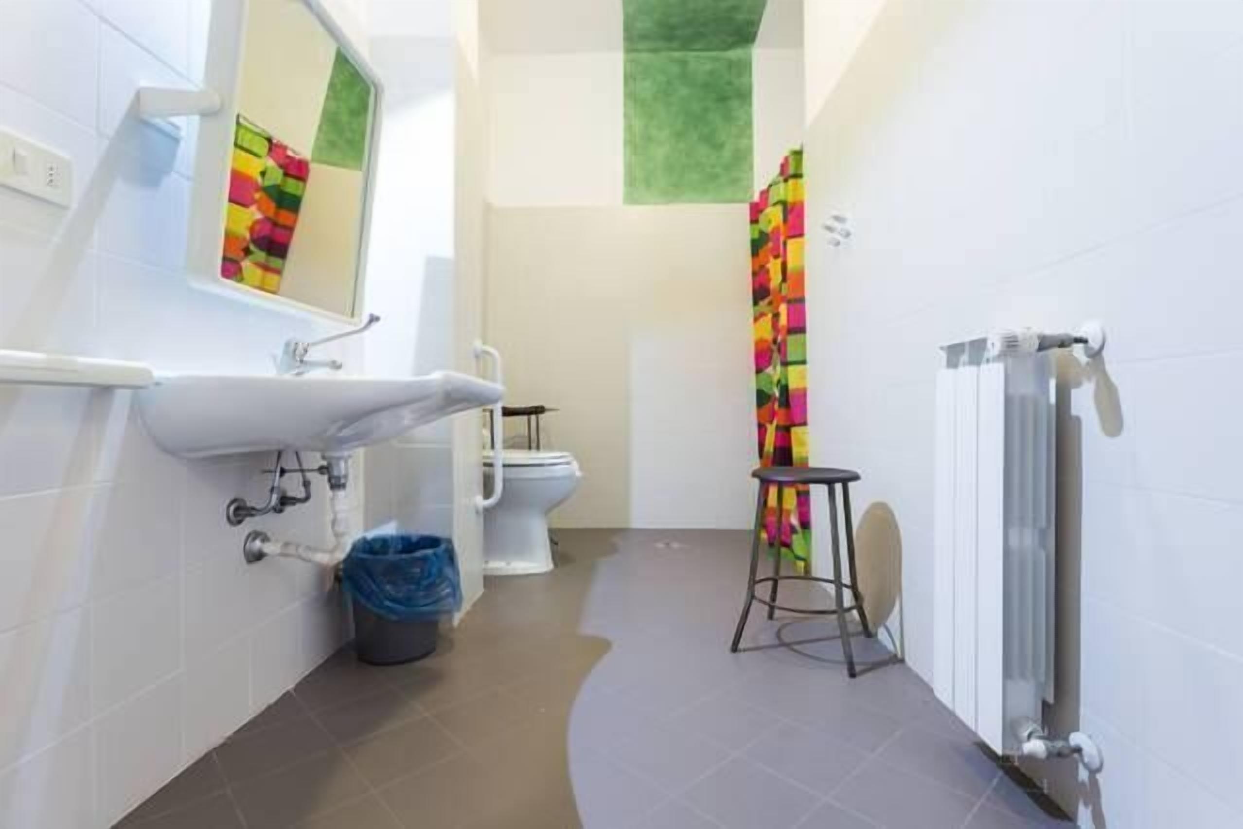 A modern bathroom with a white sink, toilet, and a colorful shower curtain.