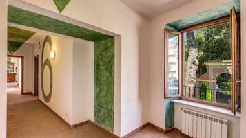 Um corredor com uma parede verde de destaque, um design circular grande e uma janela com vista para vegetação lá fora.