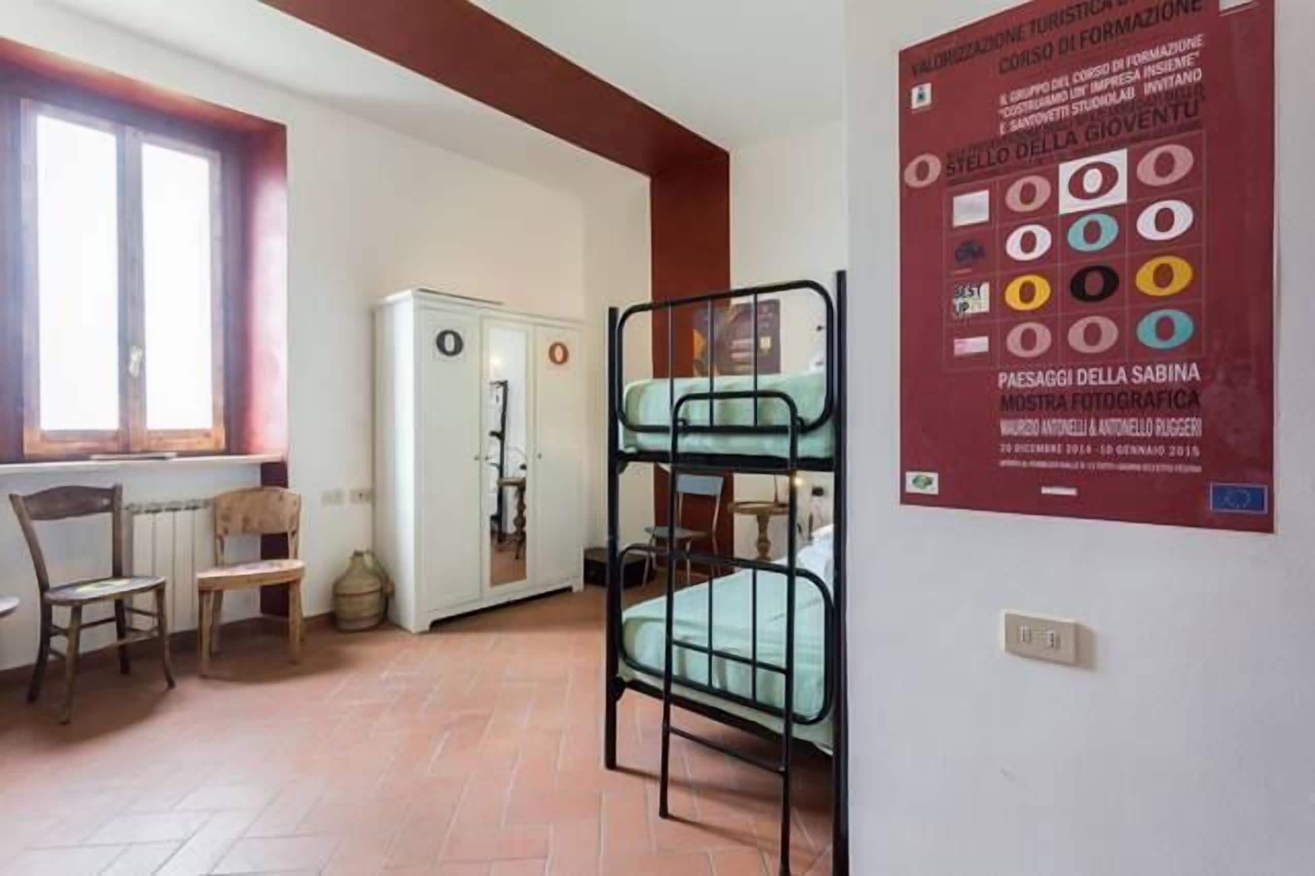 Una habitación con literas, un radiador, una ventana y un cartel en la pared.