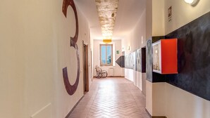 Un couloir avec un parquet en point de Hongrie, un grand chiffre « 3 » peint sur le mur et un meuble rouge sur la droite.