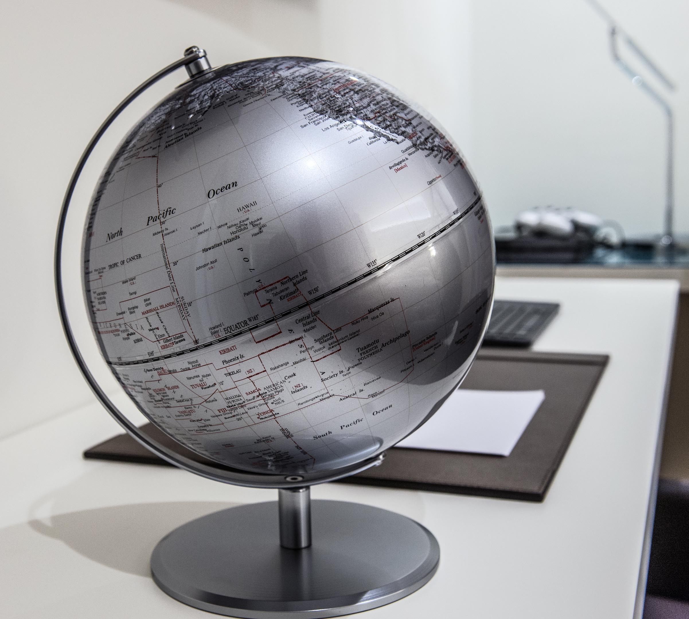 A globe on a desk with a keyboard and a mouse in the background.