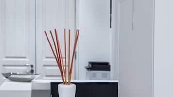 A modern kitchen with white cabinetry, a white countertop, and a vase with reed sticks.