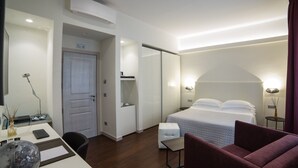 Une chambre d’hôtel comprenant un lit, un bureau, une chaise, une petite table et une lampe.