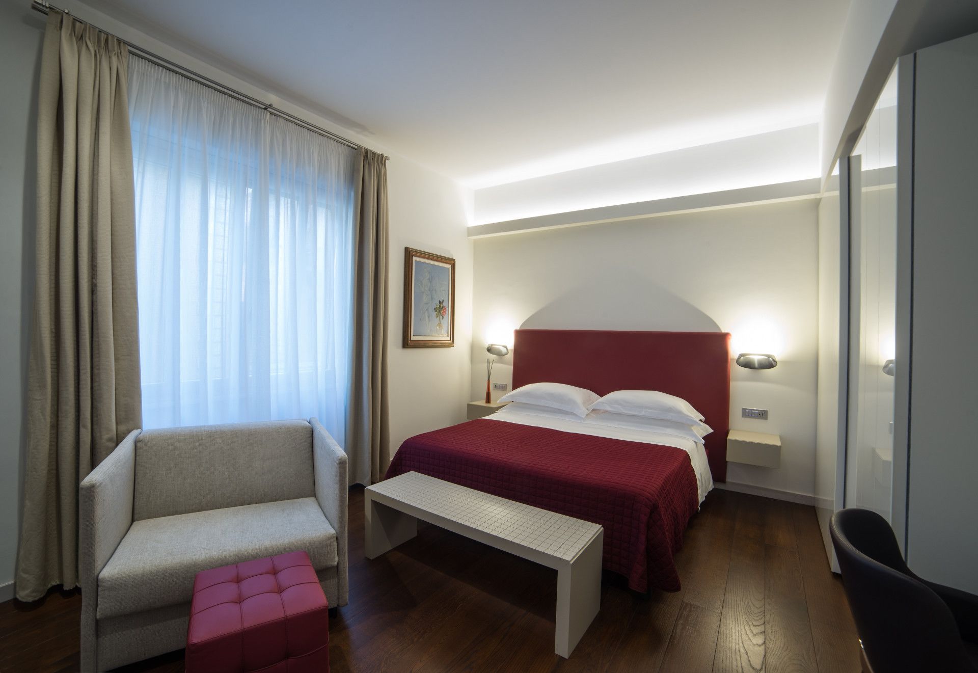 A hotel room with a bed, a sofa, a bench, and a chair.