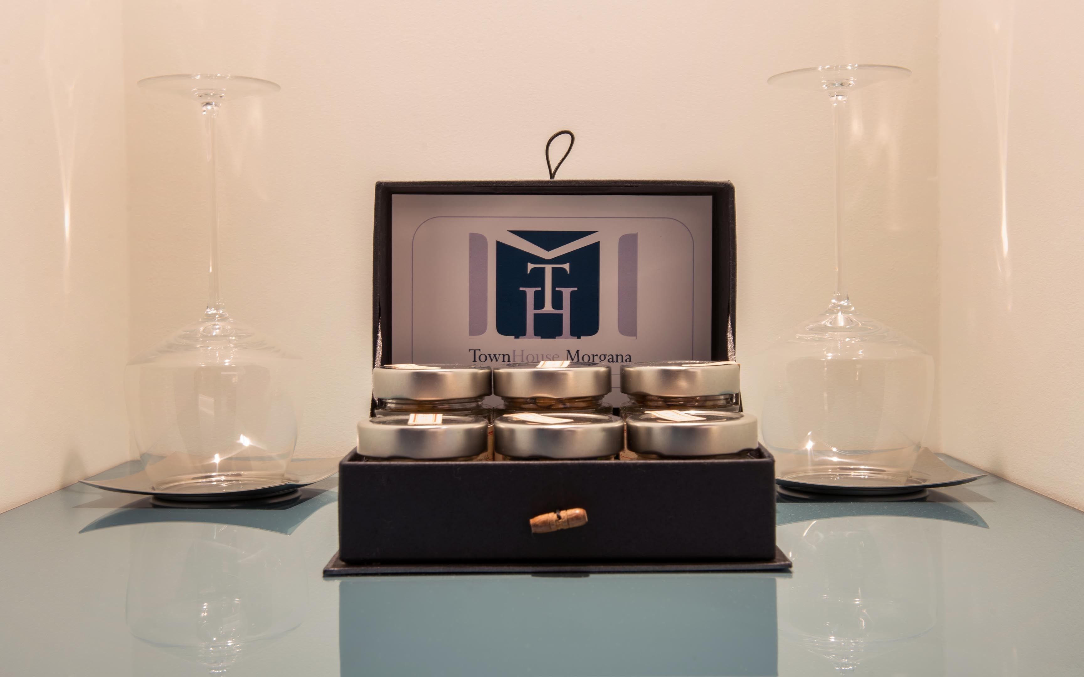 Eine Auswahl an Kerzen in einer schwarzen Box mit einem Logo und dem Schriftzug "TownHouse Morgana" auf dem Deckel.