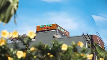 Señal de hotel con el nombre "MK TWO HOTEL" sobre un cielo azul despejado.