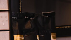 A basket containing several black and white bags with gold trim and the logo "MK Two Hotel".