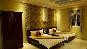 A hotel room with two beds, a wardrobe, a stone accent wall, and a window with curtains. - Minh Kieu Hotel (My Tho)