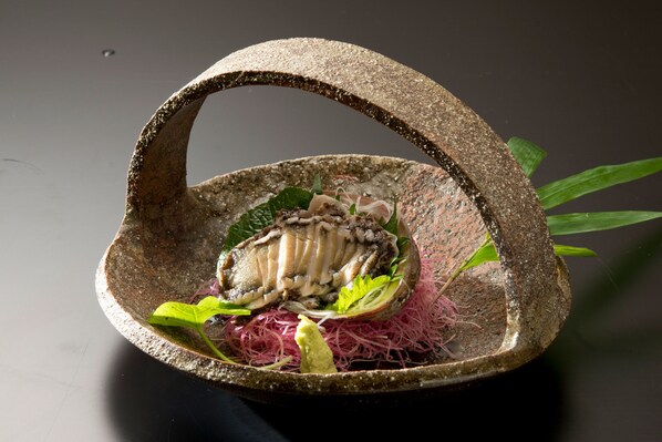 A stone bowl containing a seafood dish with greens and pink noodles. - Abba Resorts Izu - Zagyosoh (Ito)