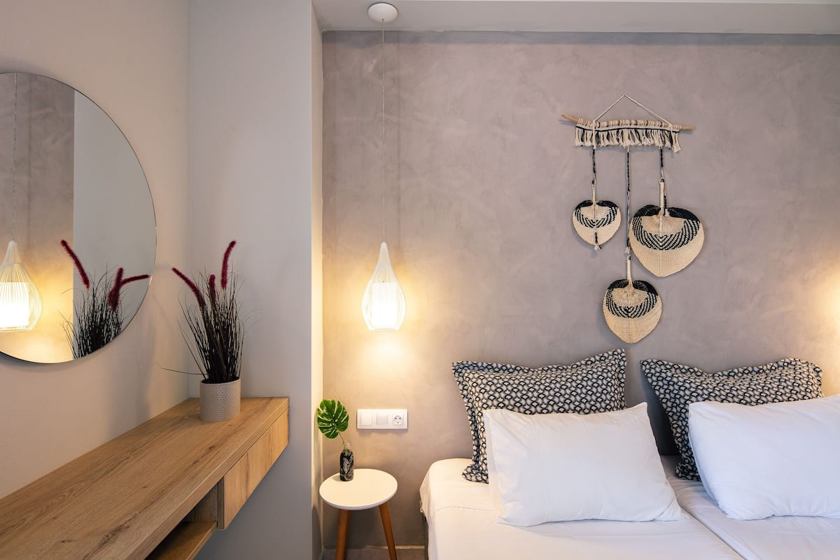 A modern bedroom with a bed, bedside tables, a mirror, and wall-mounted decor.
