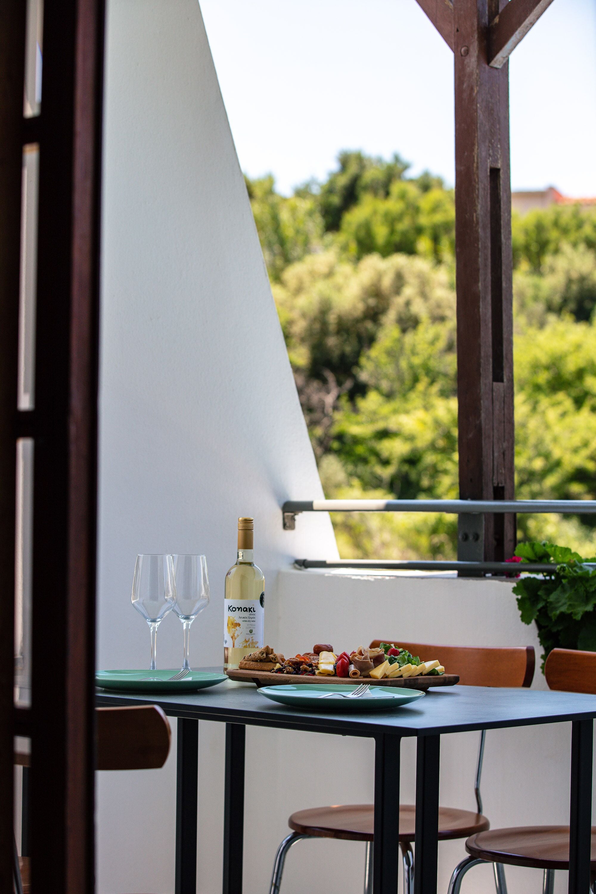 A dining table with a bottle of white wine, two wine glasses, and a plate of food.