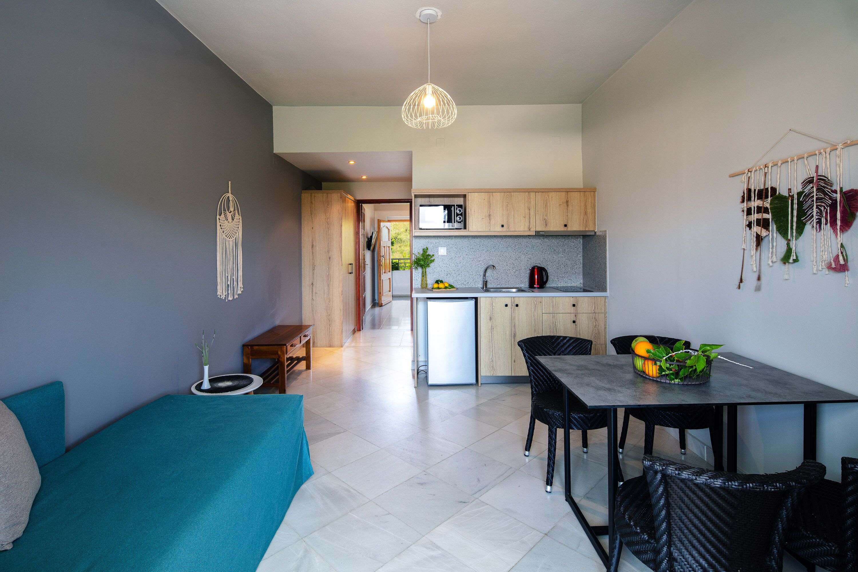 Une cuisine moderne avec des meubles en bois, un coin repas avec une table et des chaises, et un salon avec un canapé.