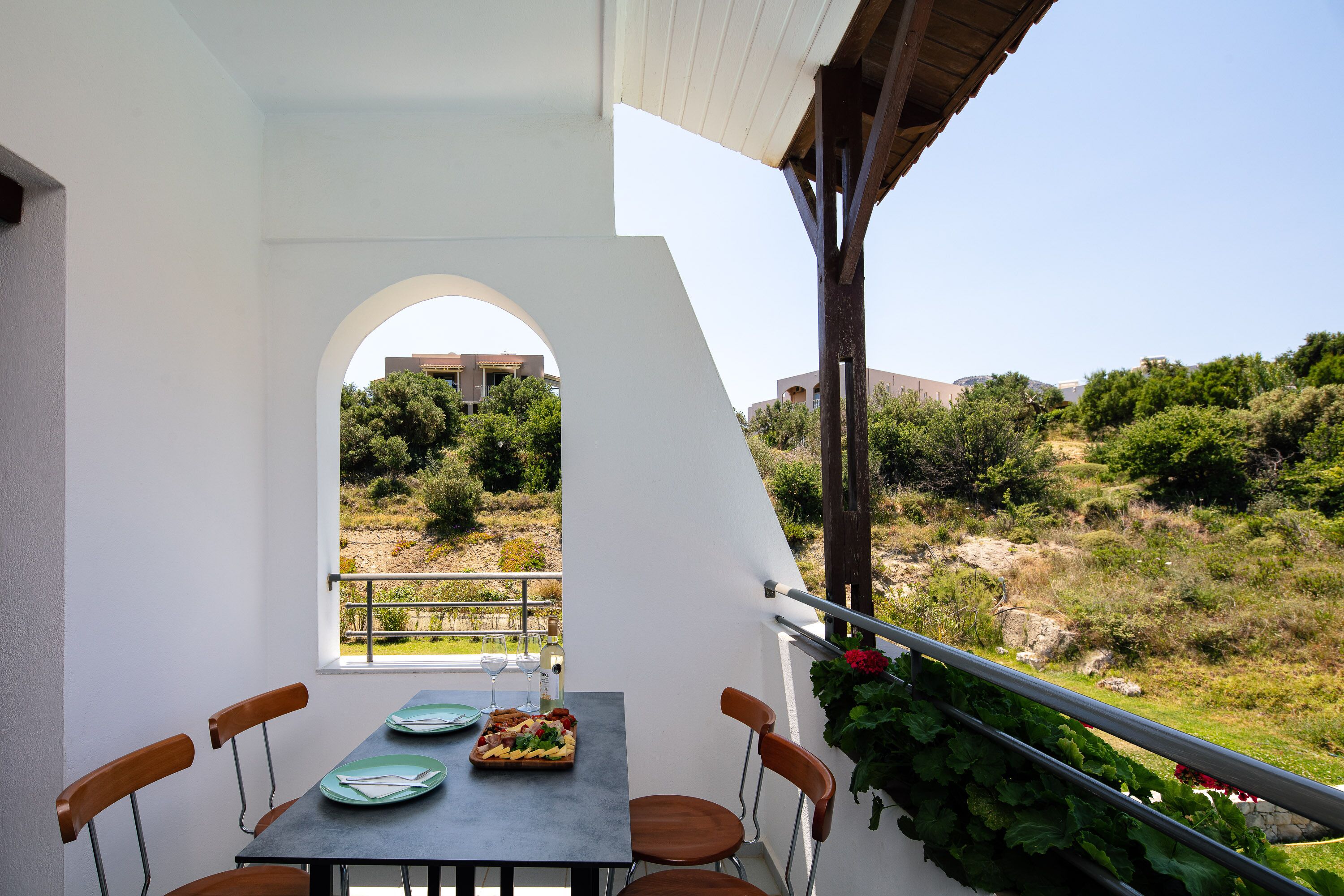 Un comedor con una mesa preparada para dos, vista del paisaje circundante y barandilla de balcón.