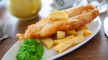 A plate of fish and chips with a lemon wedge and mushy peas.