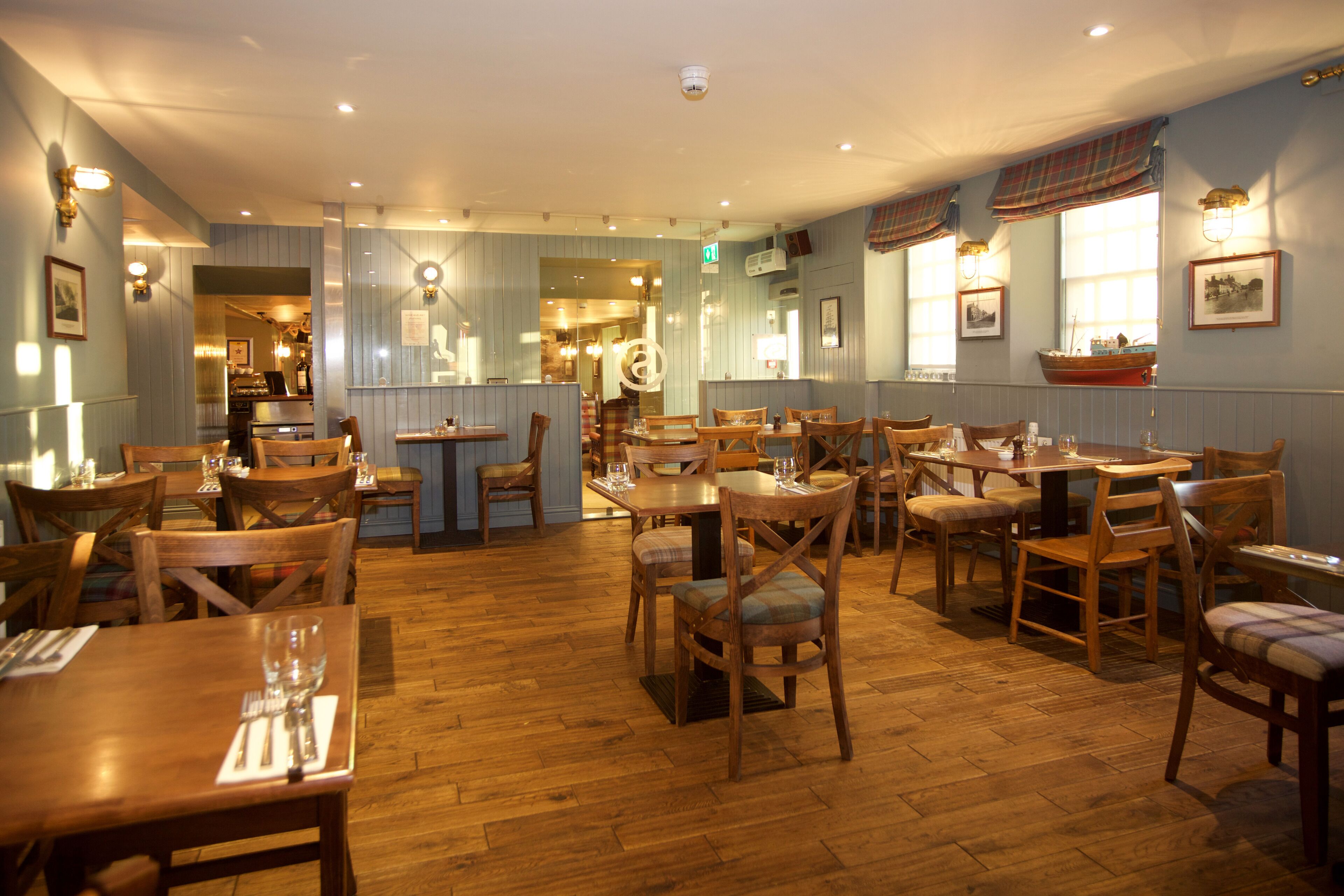 Ein Restaurant mit Holztischen und -stühlen, Holzboden und hellblauen Wänden.