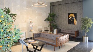 Un vestíbulo moderno con un sofá modular, dos sillones, una mesa de centro y una planta en maceta.