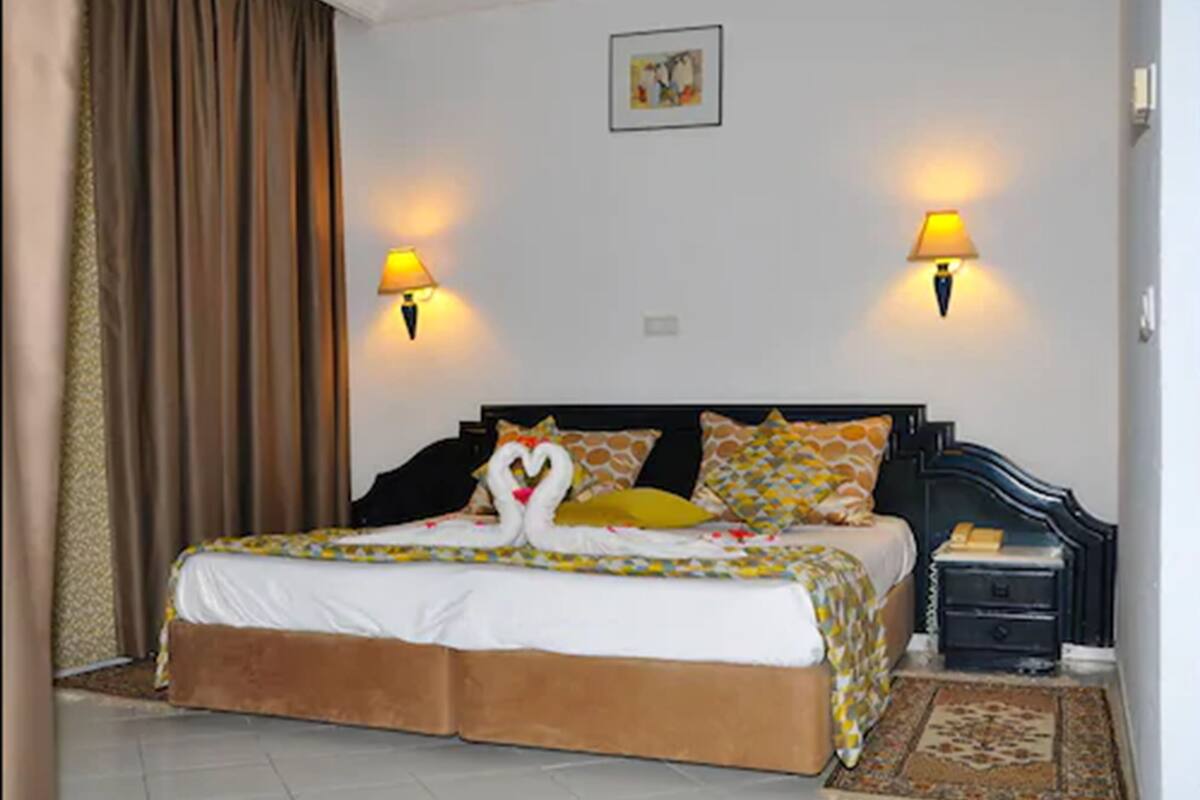 Habitación de hotel con una cama, dos lámparas de noche, una mesita de noche y una alfombra.