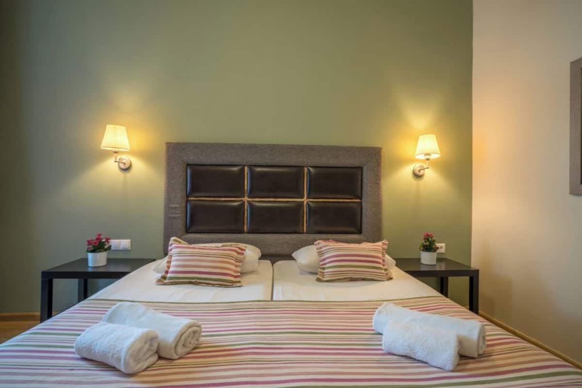 A double bed with striped bedding, two bedside tables with lamps, and a headboard with a grid pattern.