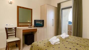 Habitació d'hotel amb llit, escriptori, cadira, televisió i armari.