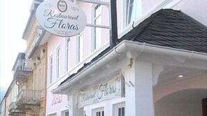 A restaurant named 'Restaurant Floras' with a signboard, outdoor seating, and a white facade. - Hotel Victoria (Schlangenbad)
