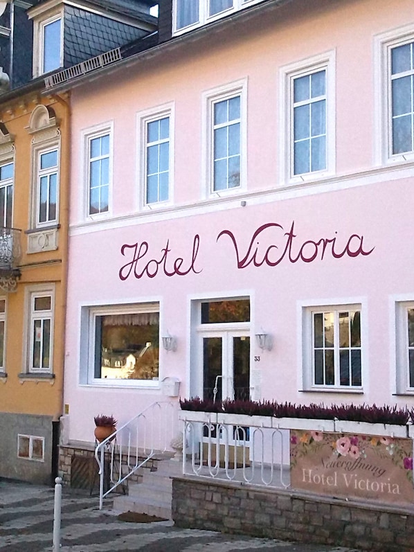 A pink building with the sign "Hotel Victoria" and a flower-adorned wall.
