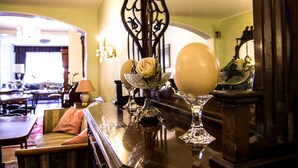 A well-lit room with a dining table, chairs, and a sofa. There is a decorative glass vase with a white rose on the table. - Hotel Victoria (Schlangenbad)