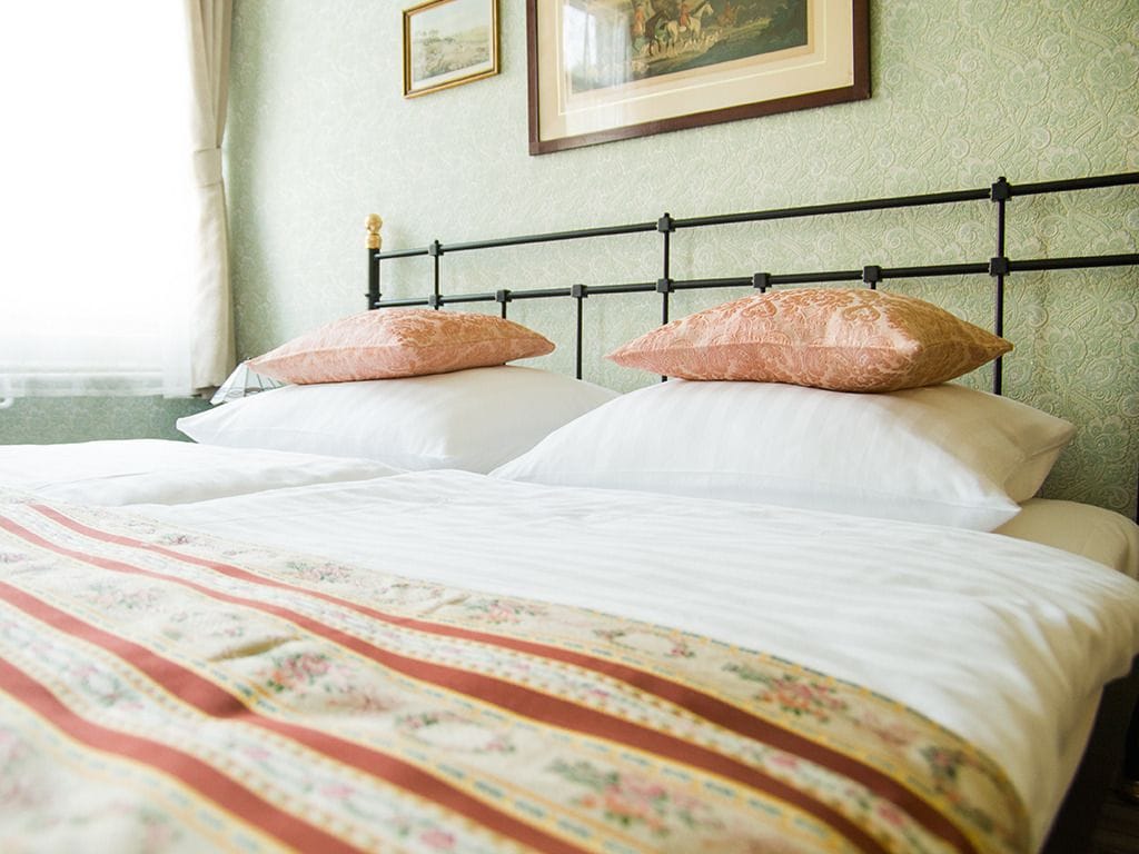 A bed with a floral-patterned bedspread, a black metal headboard, and two decorative pillows.