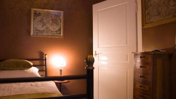 Une chambre à coucher avec un lit, une table de chevet avec une lampe, une commode et une porte.