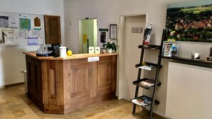 A reception desk with a wooden finish, a small plant, and a sign indicating a waiting area. - Gasthof Bären Ochsenfurt (Ochsenfurt)
