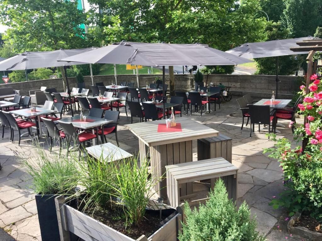 An outdoor patio with tables and chairs, umbrellas, and potted plants.