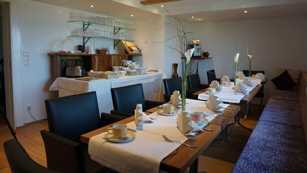 A dining area with a long table set for a meal, surrounded by chairs. - Hotel Waldrast B&B (Zwischenwasser)