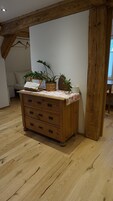Un aparador de madera con cajones, un mantel floreado y dos plantas en macetas.