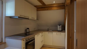 A compact kitchen with white cabinets, a stainless steel stove, a built-in oven, and a sink. - Hotel Waldrast B&B (Zwischenwasser)