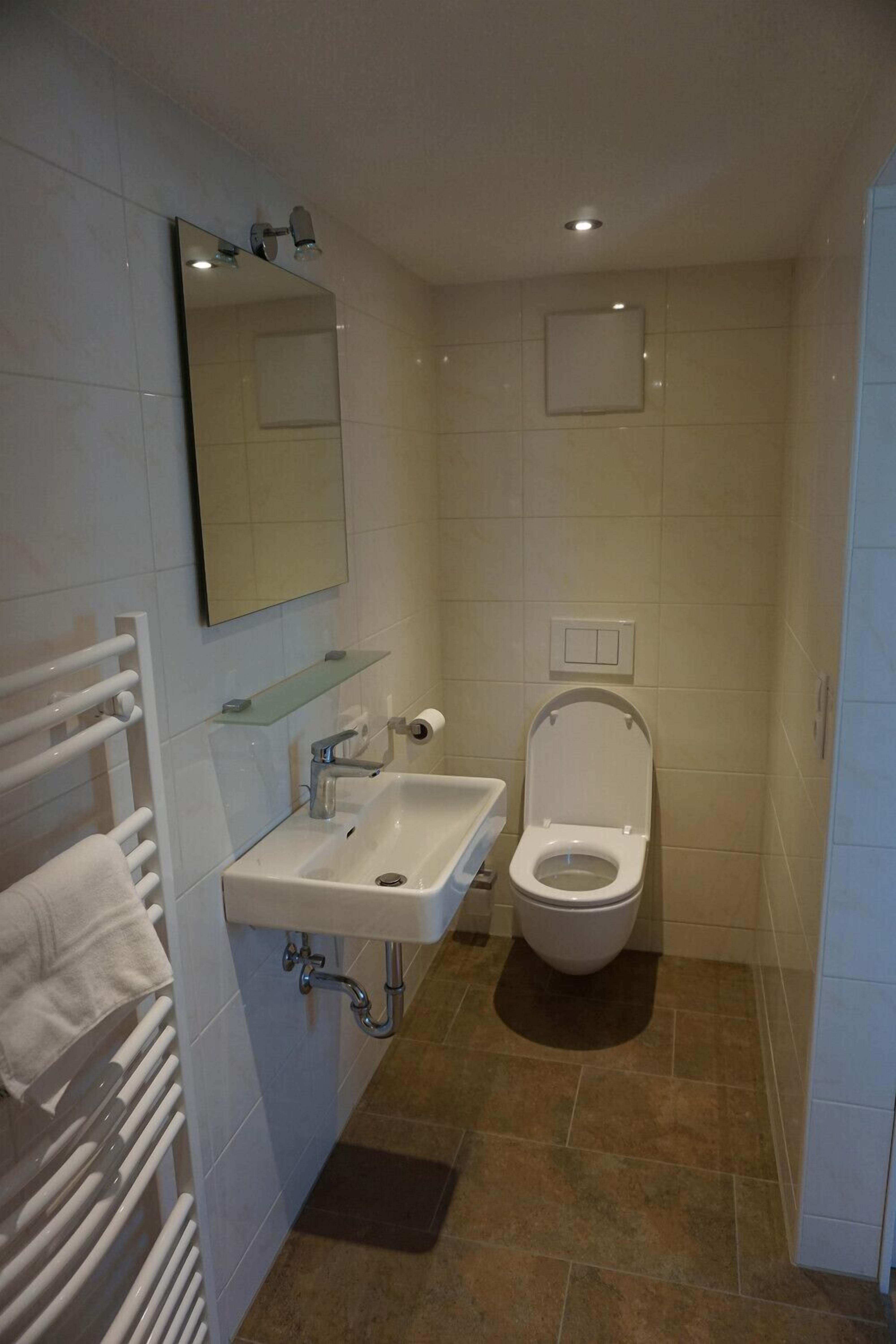 A bathroom with a white sink, mirror, and toilet.
