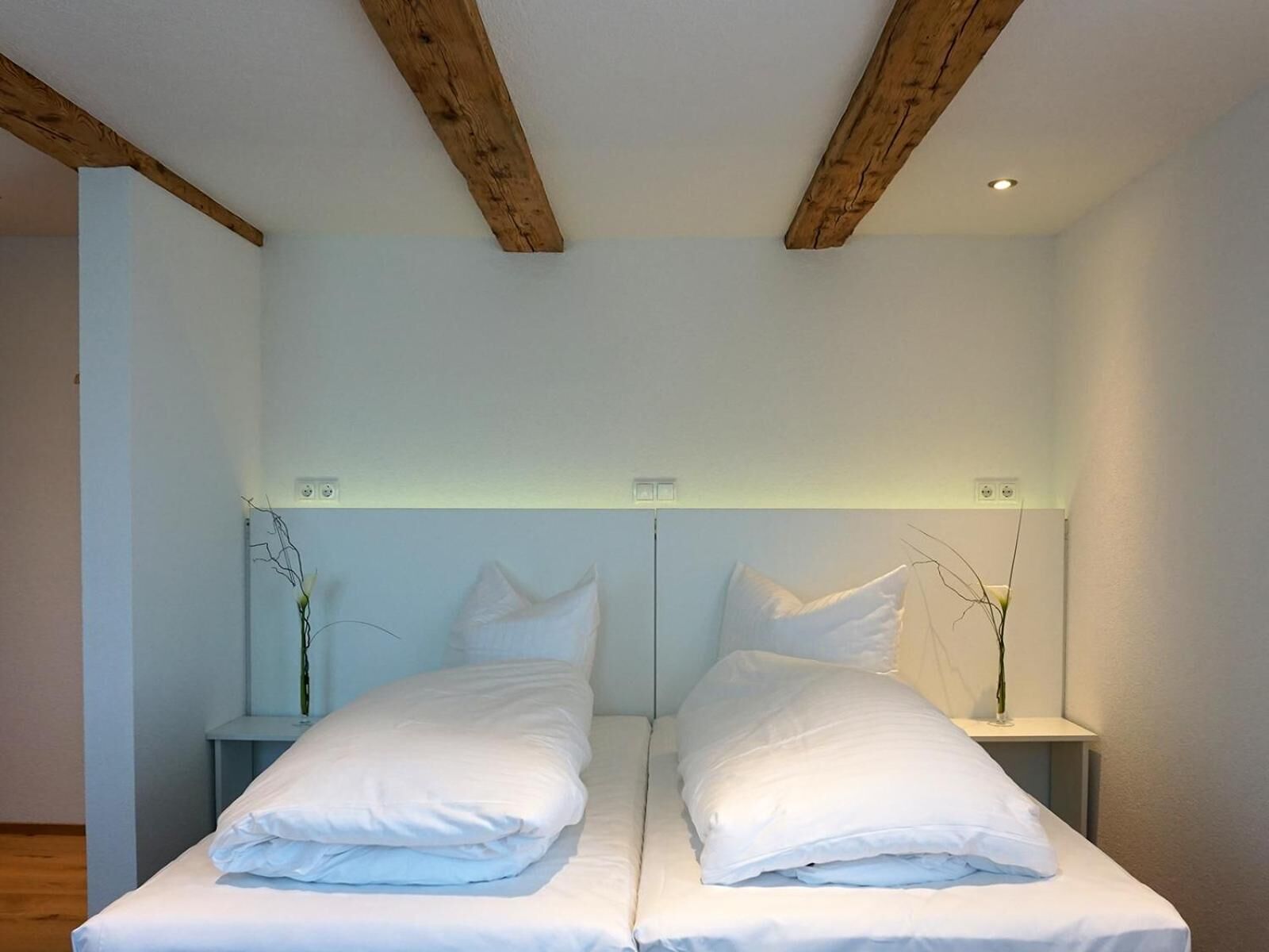 A double bed with white linens in a room with a simple, clean design.