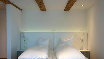 A double bed with white linens in a room with a simple, clean design.